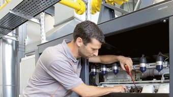 Wartungsarbeiten durch einen jungen Techniker an einer Heizung