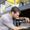 Wartungsarbeiten durch einen jungen Techniker an einer Heizung