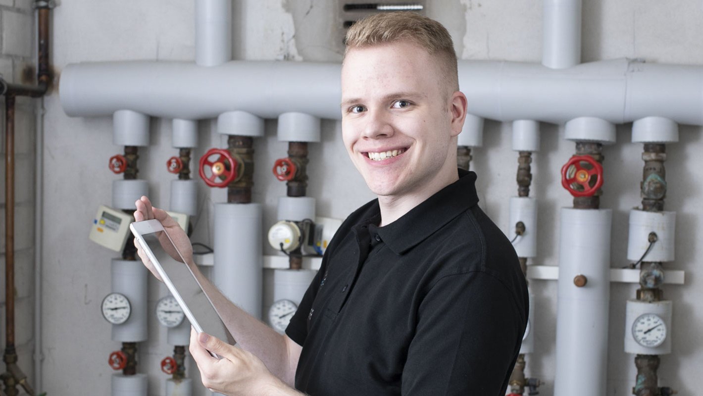 Ein Anlagenmechaniker vor einer Heizungsanlage mit einem Tablet