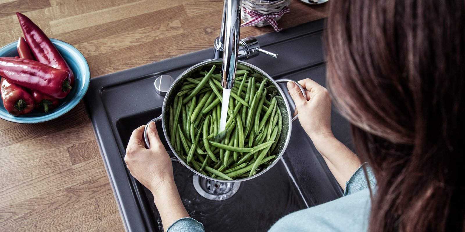 Eine Frau die die ein Topf mit Bohnen unter dem Wasser abspuehlt